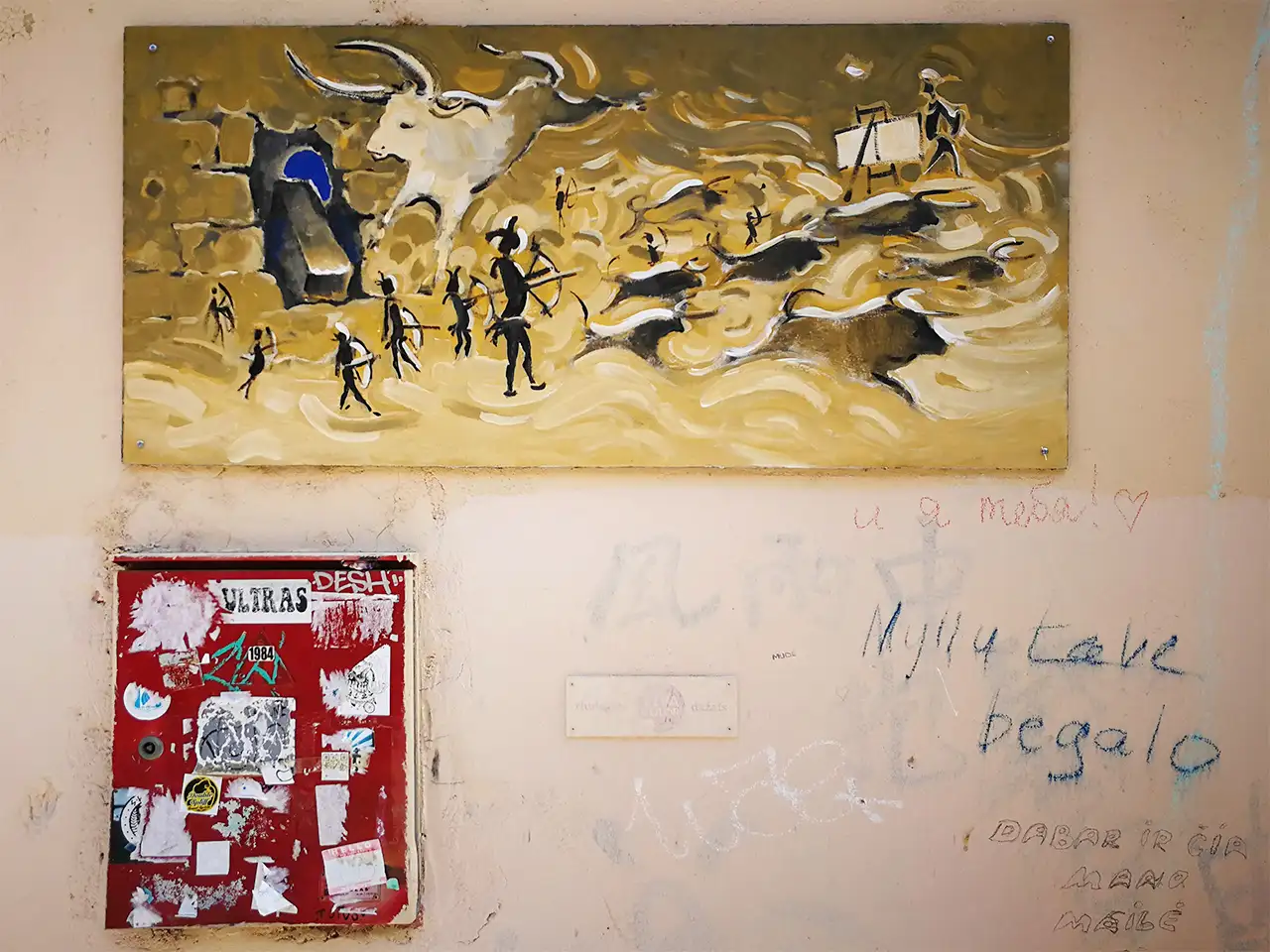 Фрагмент на фасада на сграда с облепена от стикери червена пощенска кутия, богата на асоциации картина и небрежни надписи на различни езици