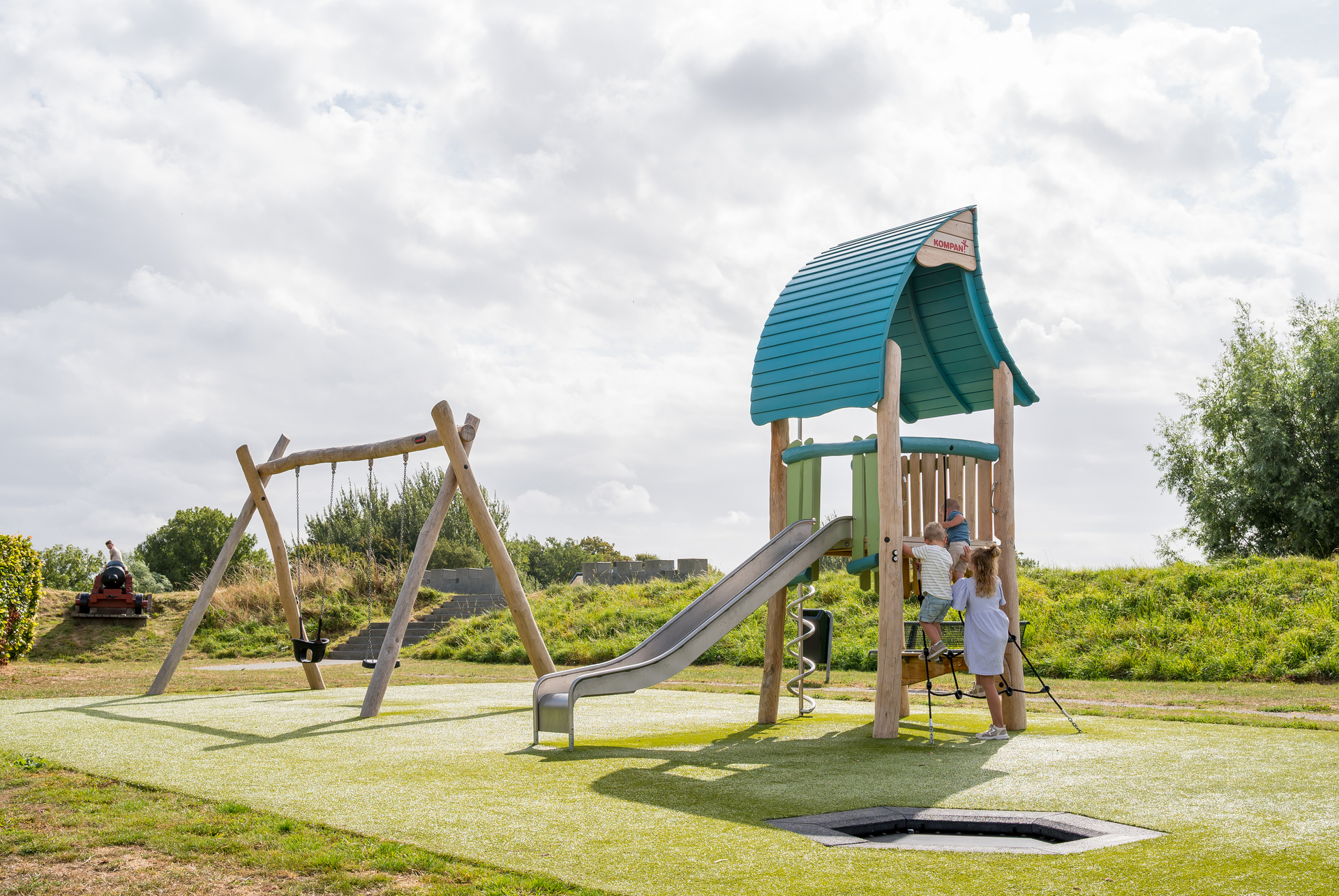 Een ABOS-medewerker staat in het zand en inspecteert een speeltoestel
