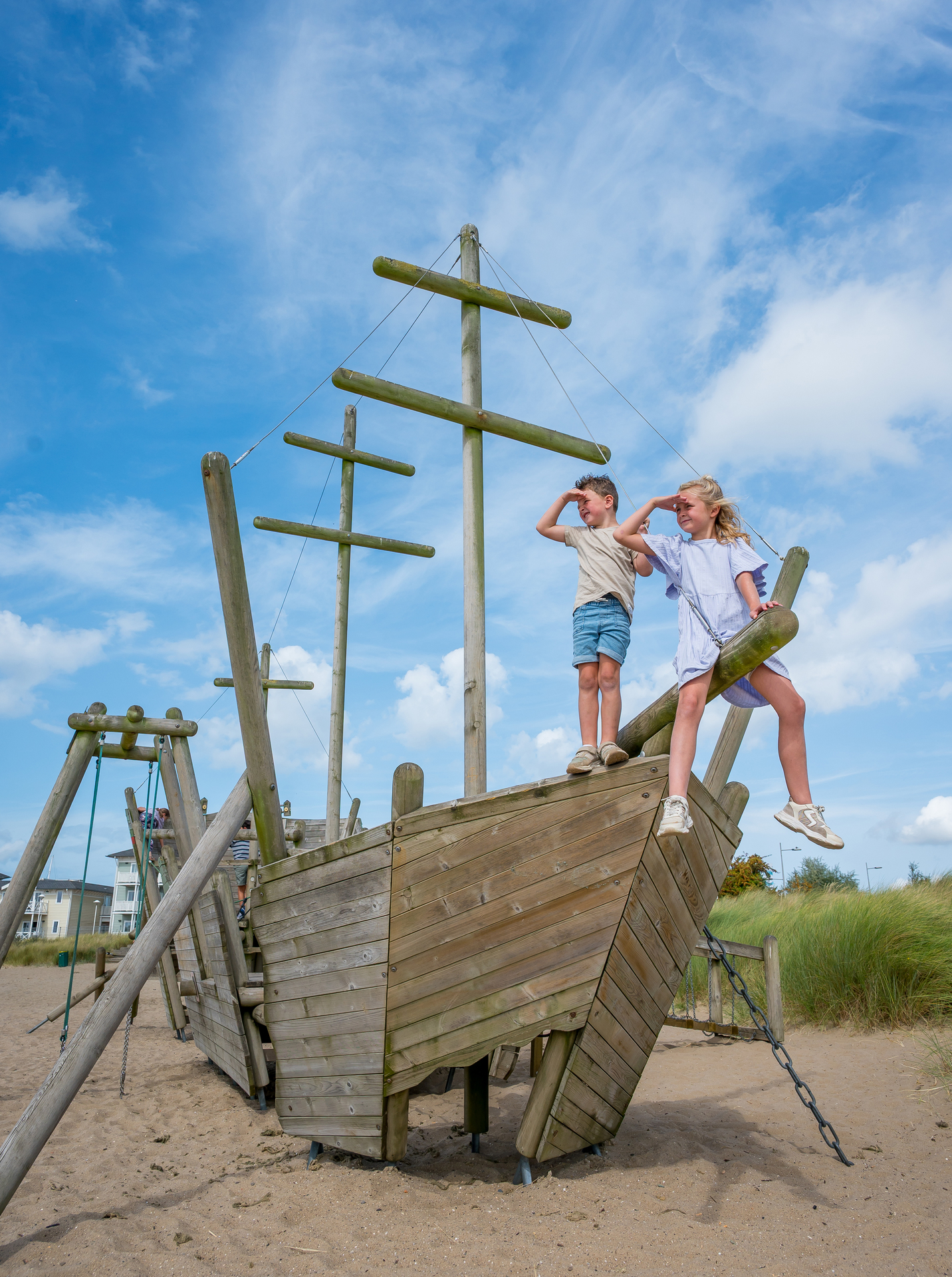 Een ABOS-medewerker staat in het zand en inspecteert een speeltoestel