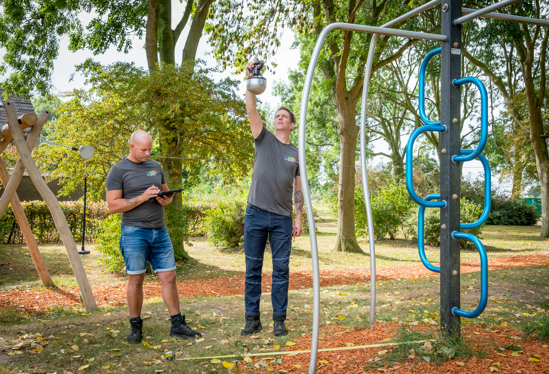 Een man die een mobiele telefoon vasthoudt in een speeltuin