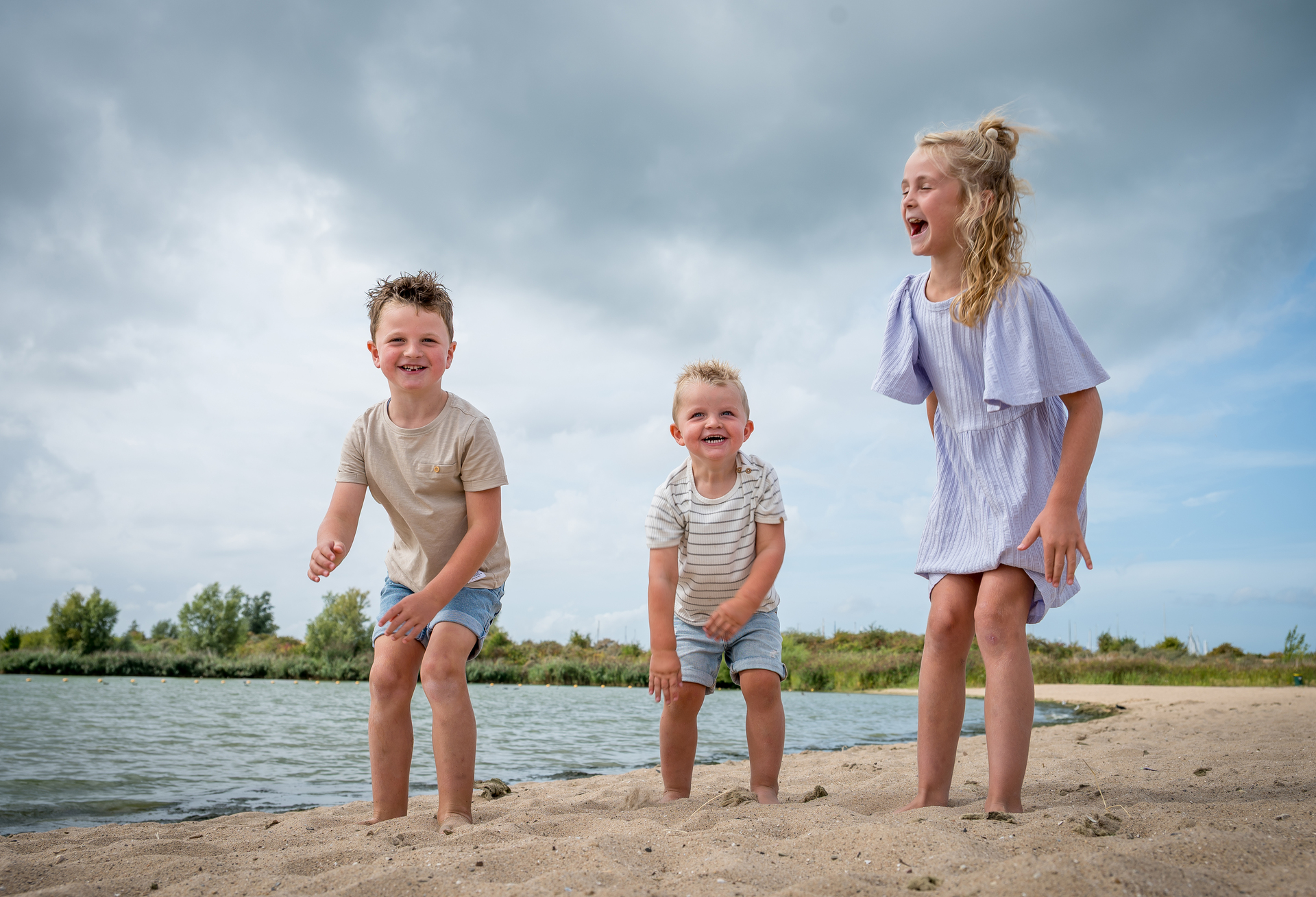 Een blond meisje glijdt van een houten speeltoestel aan het water in Vinkeveen