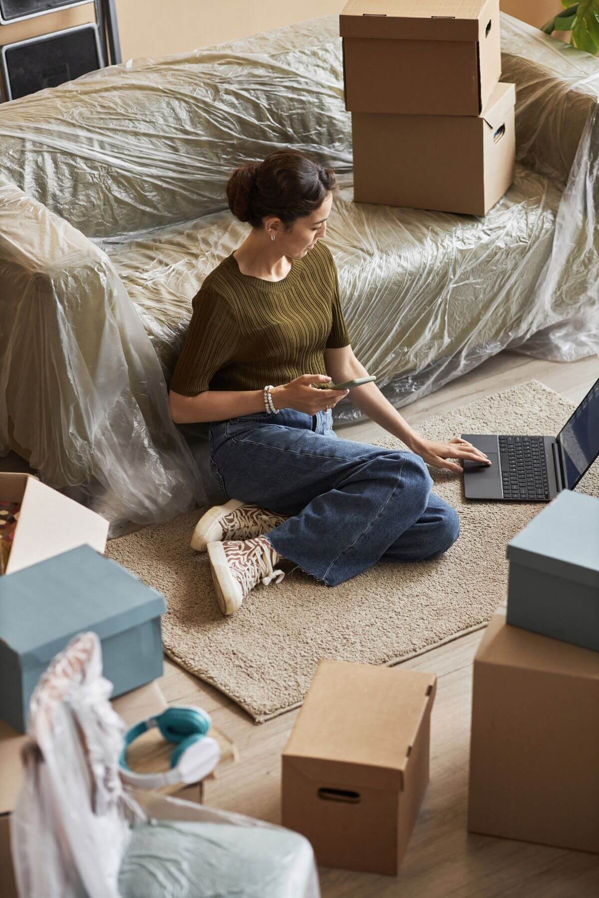 Woman surrounded by moving boxes working on a laptop