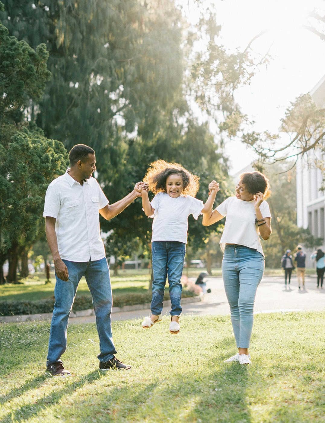 A couple playing with their young daughter at a park.