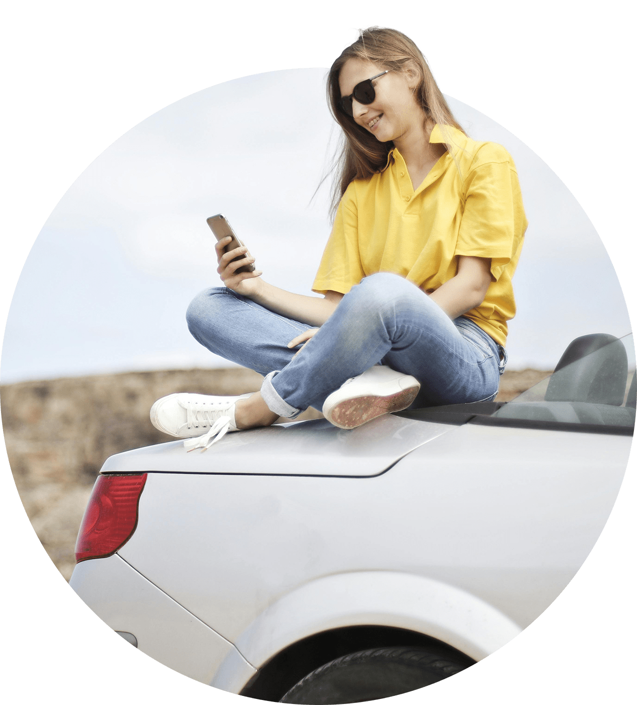 Young woman sitting on a car and using a smart phone