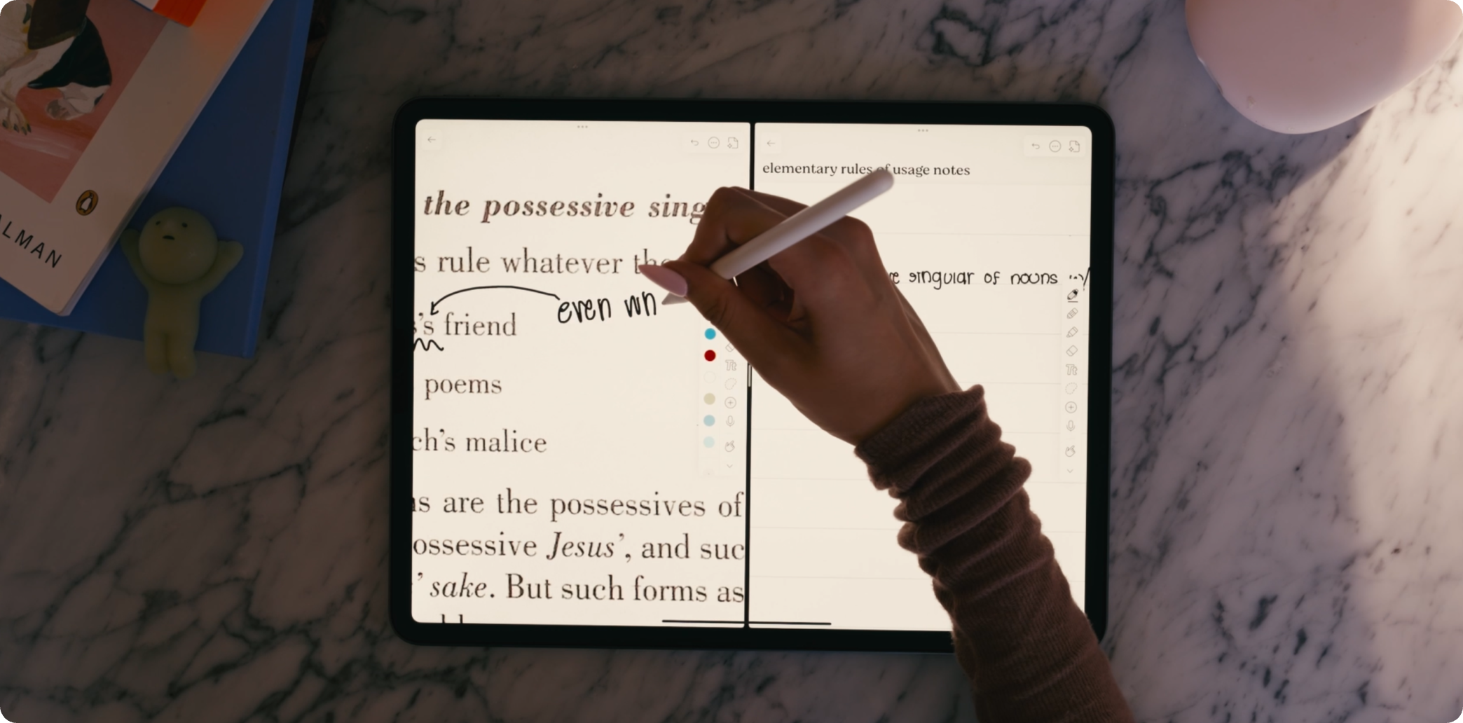 A hand takes digital notes and looks at another document via split screen on an iPad on Notability.