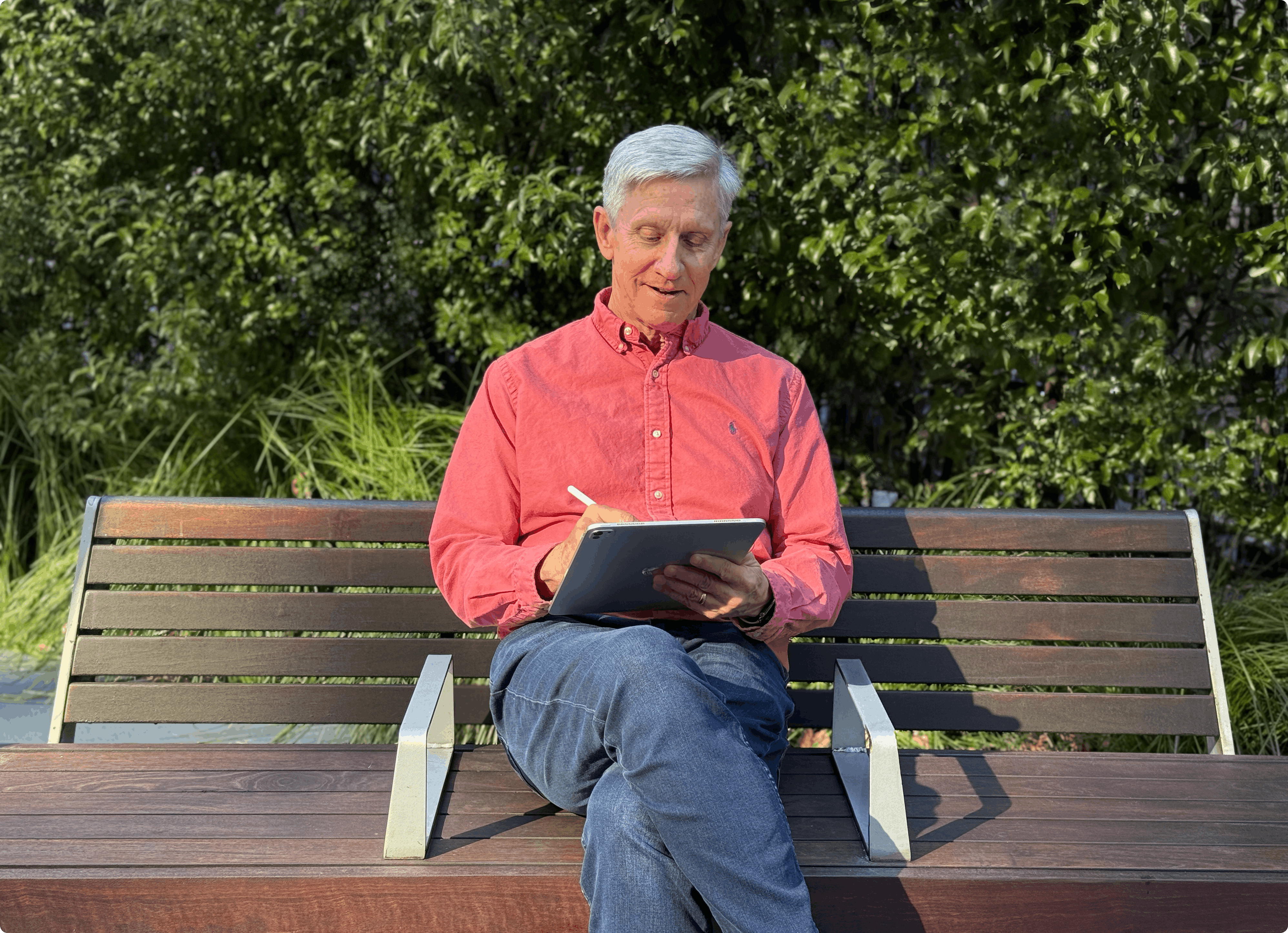 A man sits on a park bench and uses Notability on his iPad with an Apple Pencil.