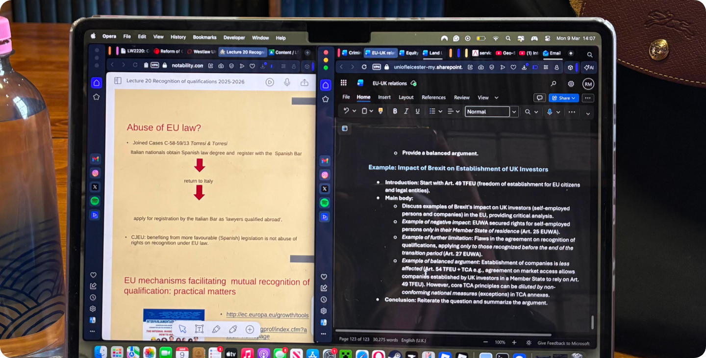 A laptop is open on a university library table, with a Microsoft Word doc and Notability open up on a split screen.