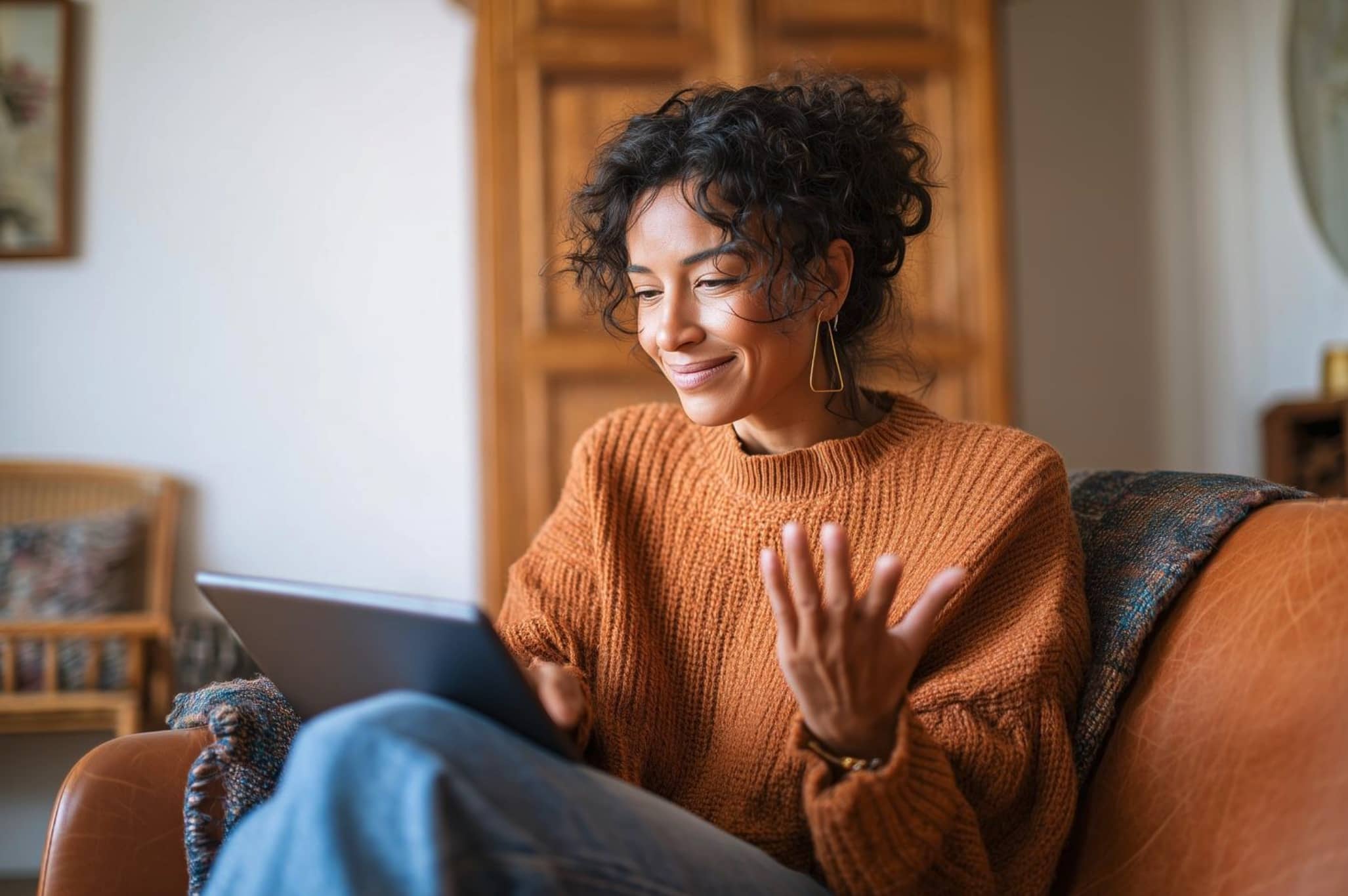 Woman in an orsweater sitting comfortably on a couch browsing a tablet for answers