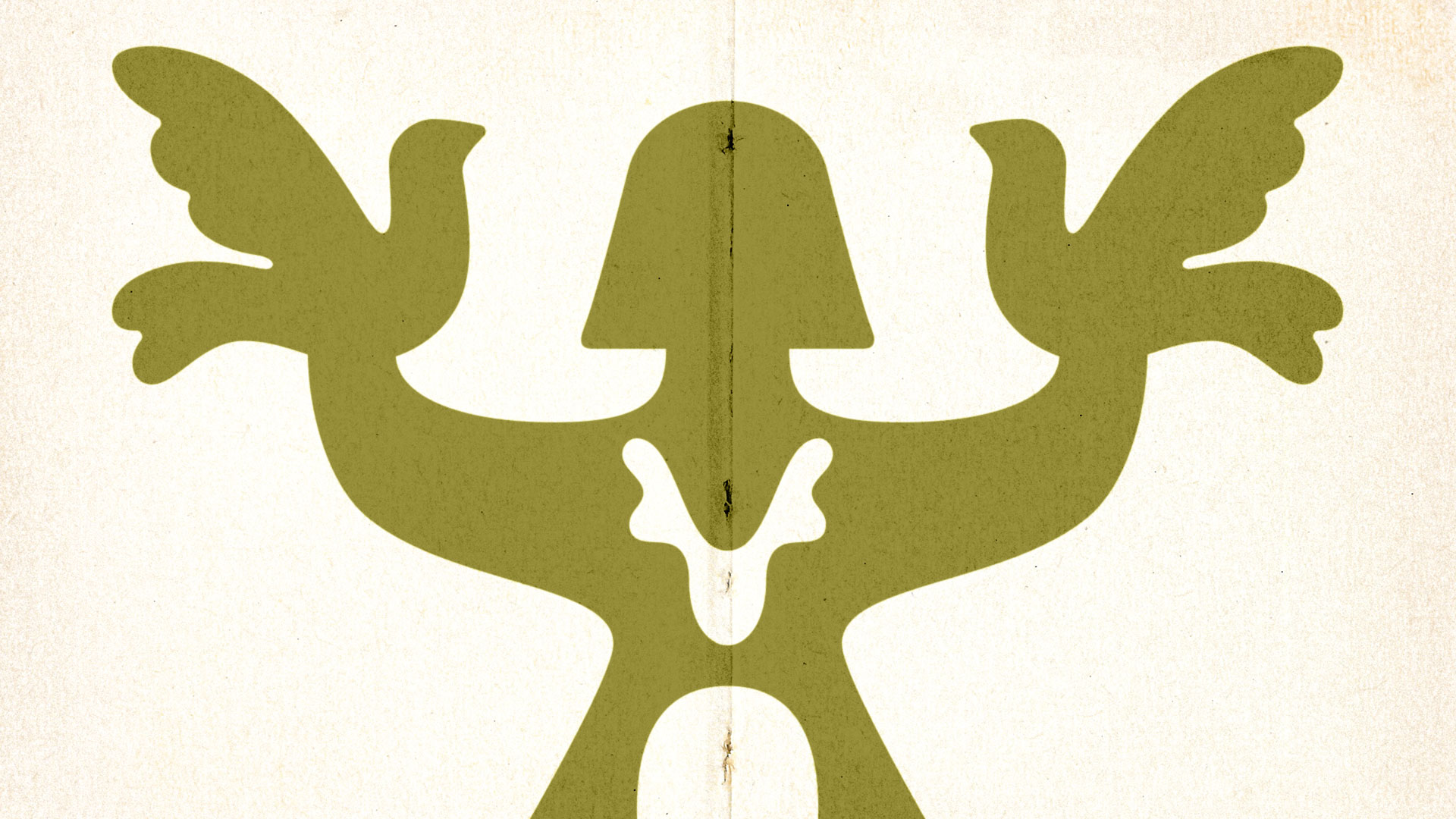 Large illuminated yellow advertisement with Ukrainian text displayed on a building, partially obscured by a leafless tree at night.