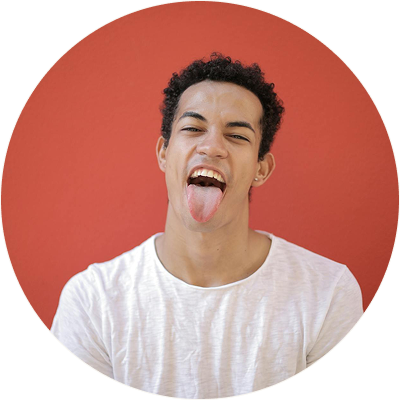 Young man with curly hair wearing a white shirt sticking his tongue out against a red background.