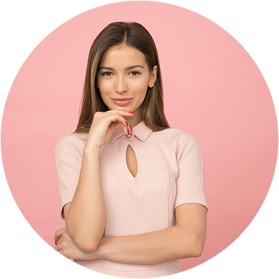 Young woman with long brown hair wearing a light pink top, posing with one hand near her chin against a pink background.