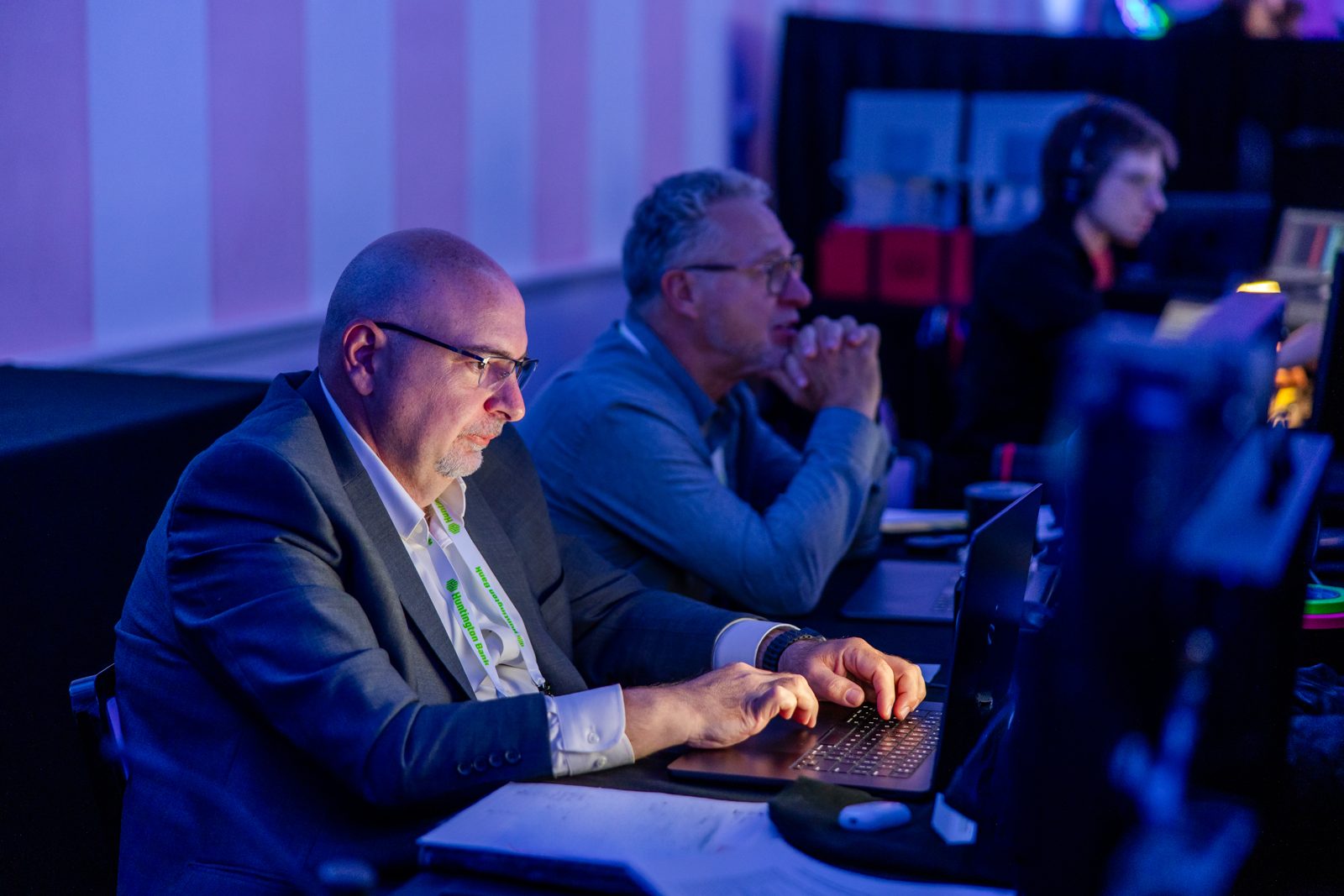 Two Creative Day team members working at a laptop in a darkened event control area