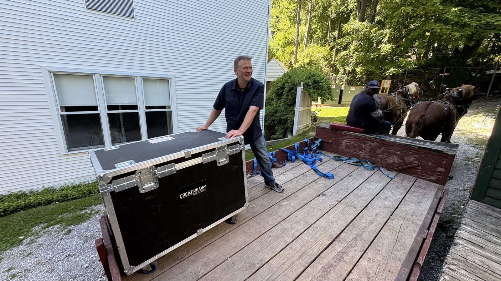 A Creative Day team member loading a road case onto a horse-drawn dray