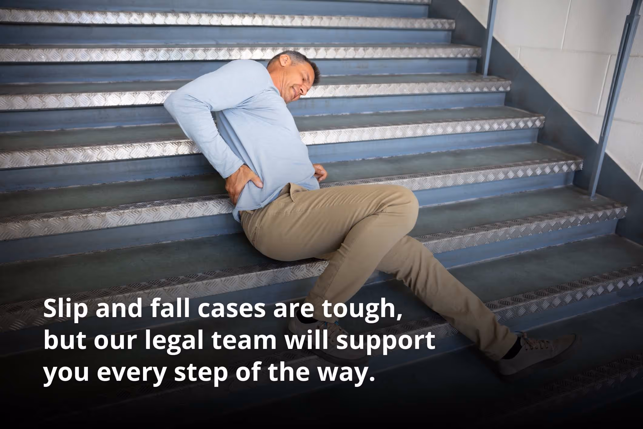 A man lying on a staircase who may qualify for a slip and fall lawsuit.