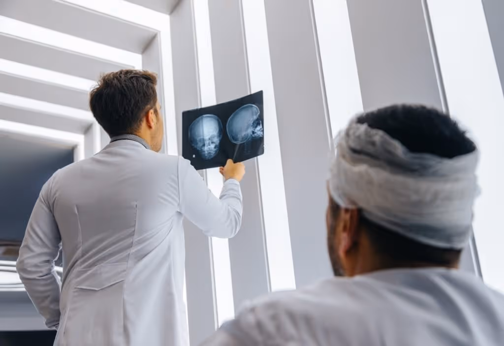 Doctor examining skull x-ray in front of patient with white head bandage