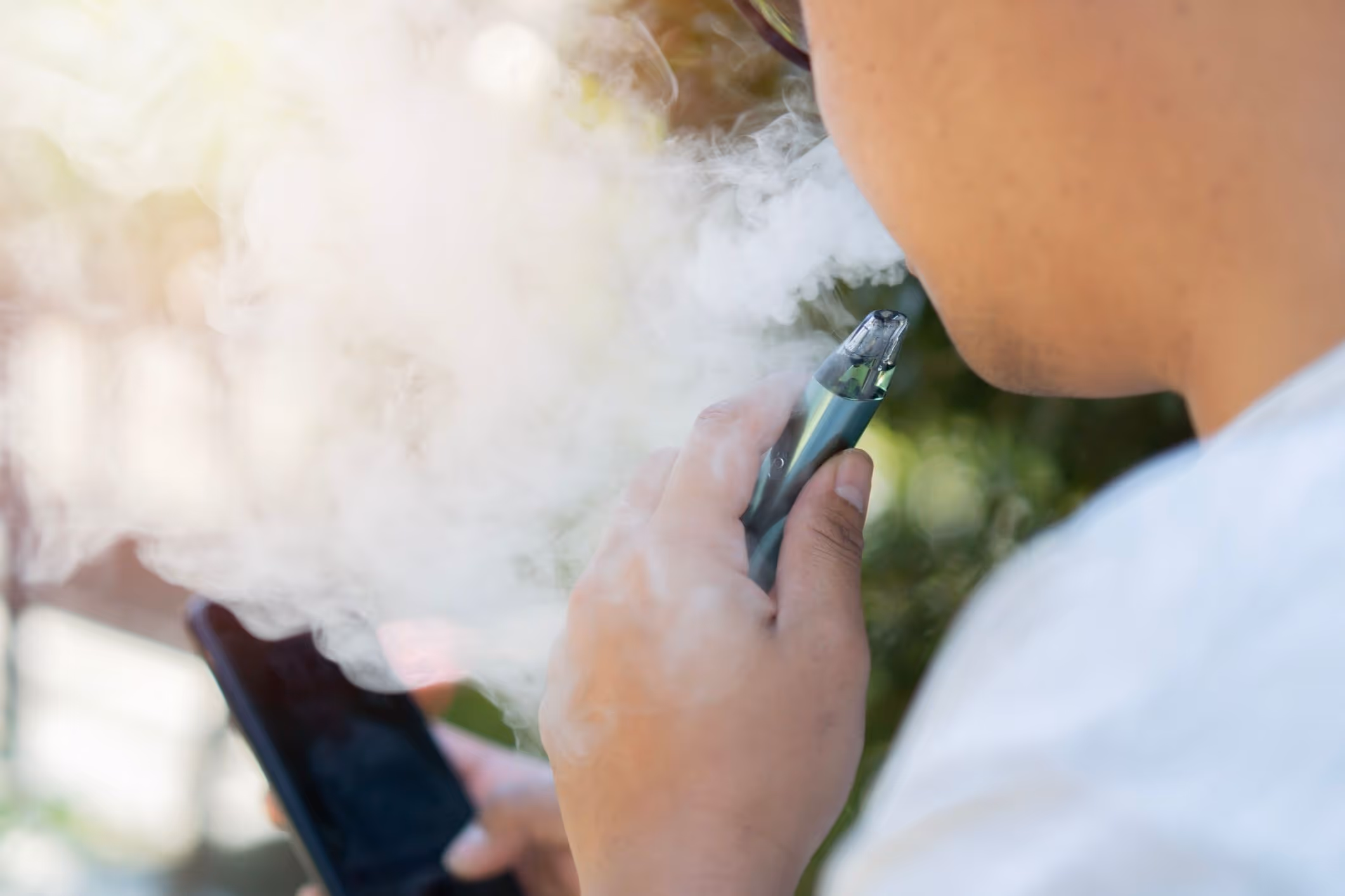 Back view of smoking man holds electronic cigarette.