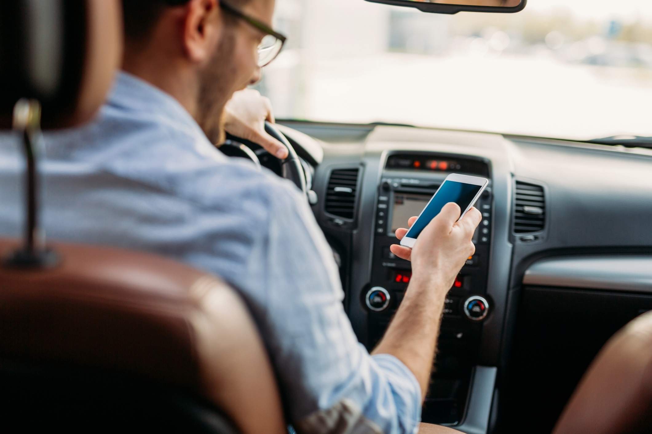 Man looking at mobile phone while driving.