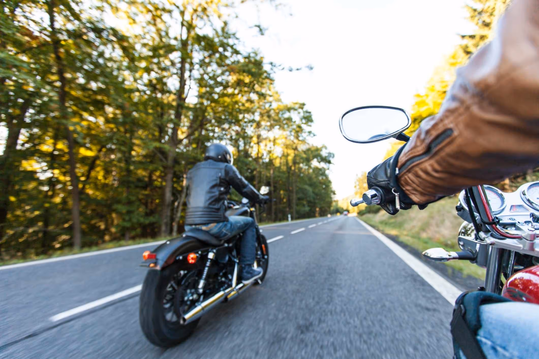 Man seated on a motorcycle along a forested road, representing a Yorktown motorcycle accident lawyer helping injured riders after crashes.