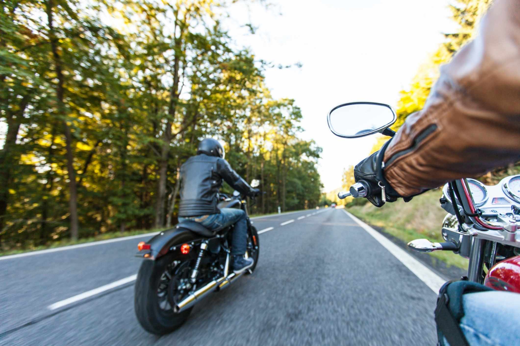Man seated on a motorcycle along a forested road, representing a Yorktown motorcycle accident lawyer helping injured riders after crashes.
