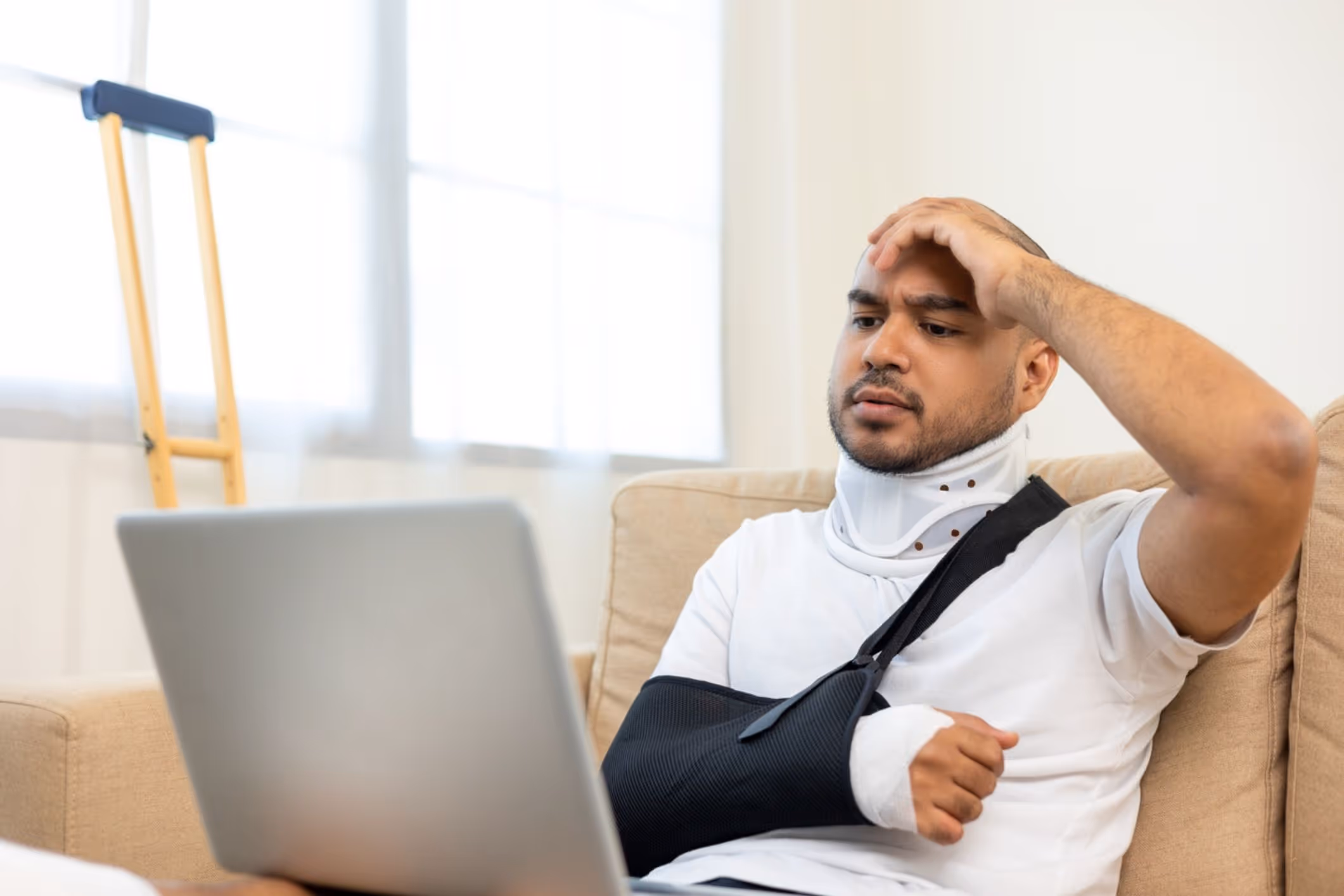 Man with arm in splint using crutches at home, representing recovery with help from a Portsmouth personal injury lawyer.