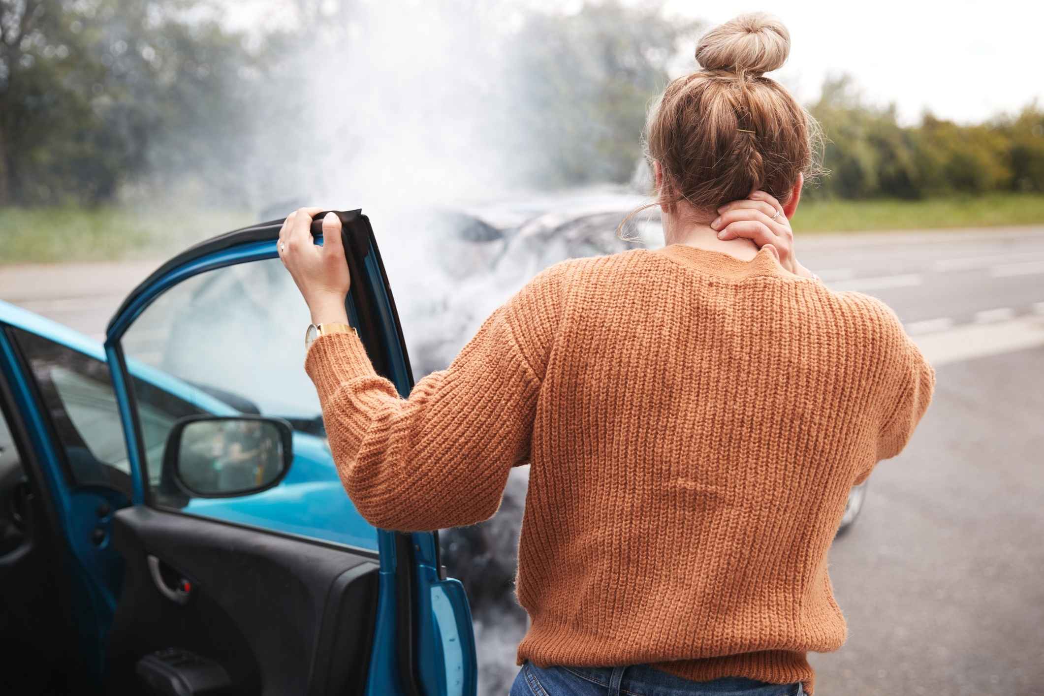 Young woman is holding her neck after a car accident.