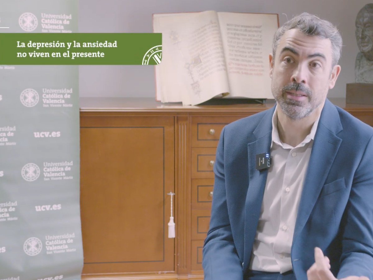 Man speaking in an interview setting with a banner about depression and anxiety in the background.