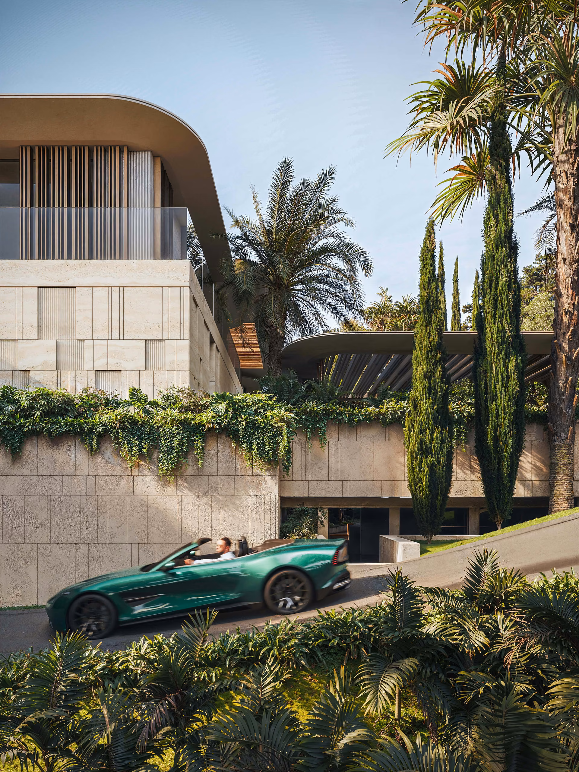 Garage entrance beneath planted terraces, with palms, cypresses and a green convertible.