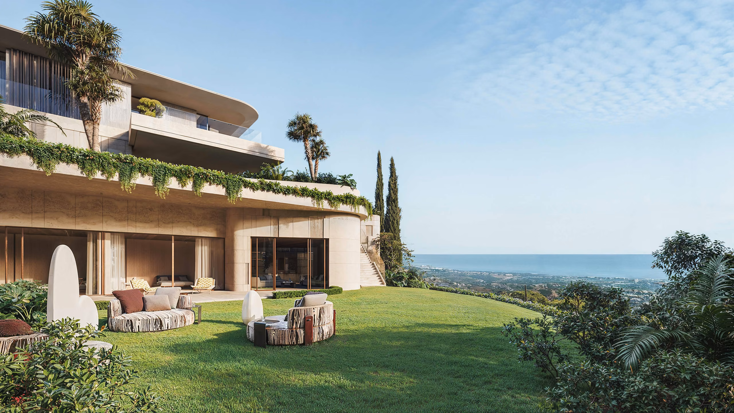 Garden seating facing the glazed facade and balconies, with the sea beyond.