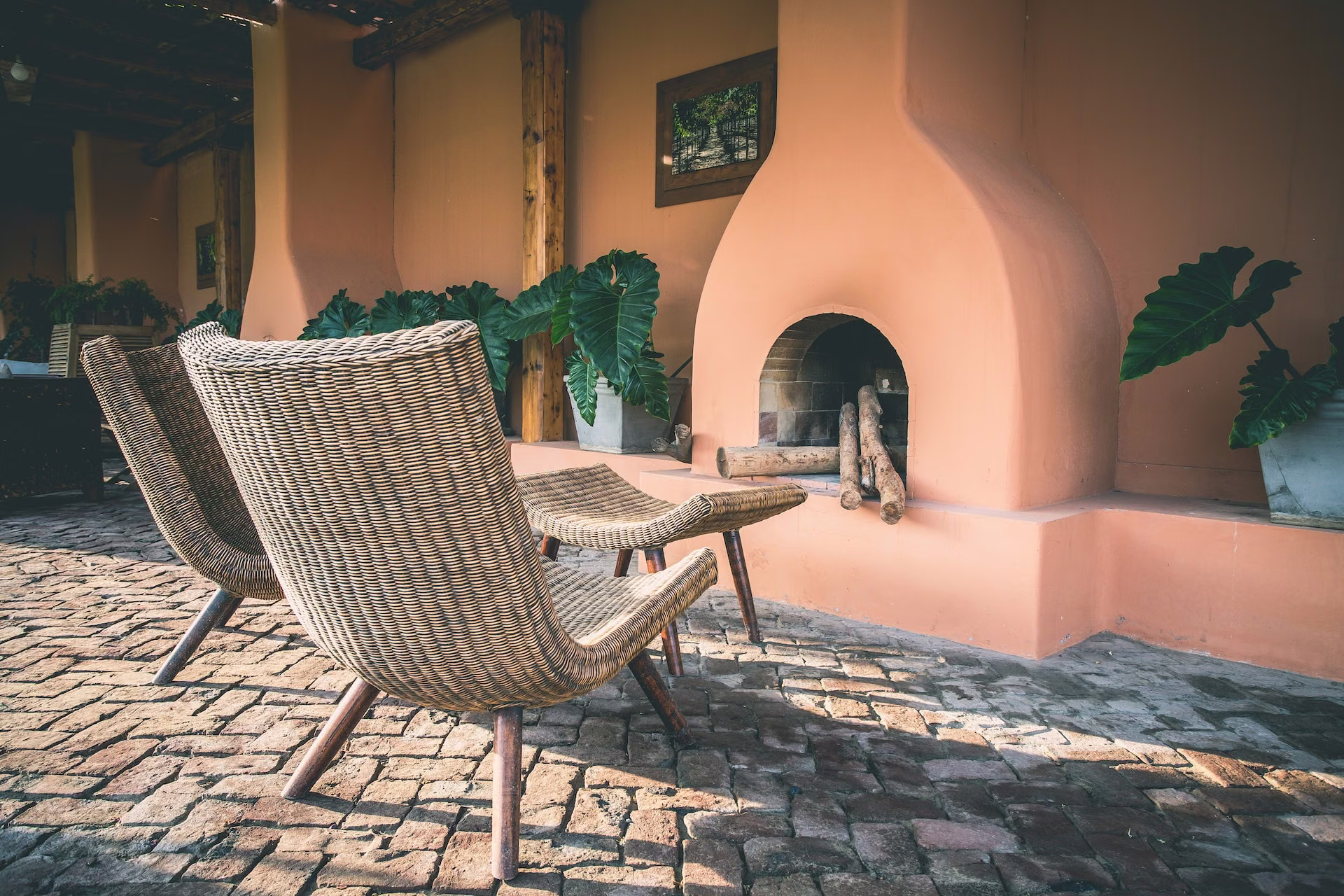 Illustrative sheltered terrace with wicker seating and a terracotta fireplace