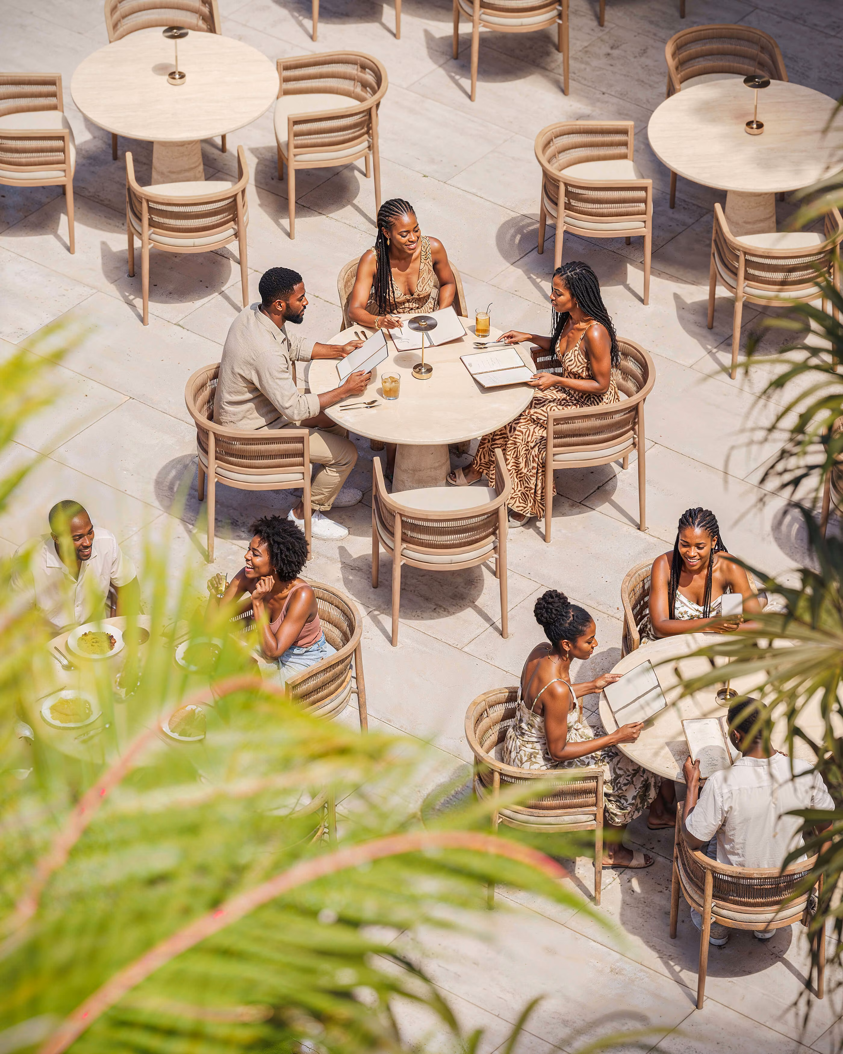 Elevated view of the Aqquaaba terrace with round tables, chairs and people talking.