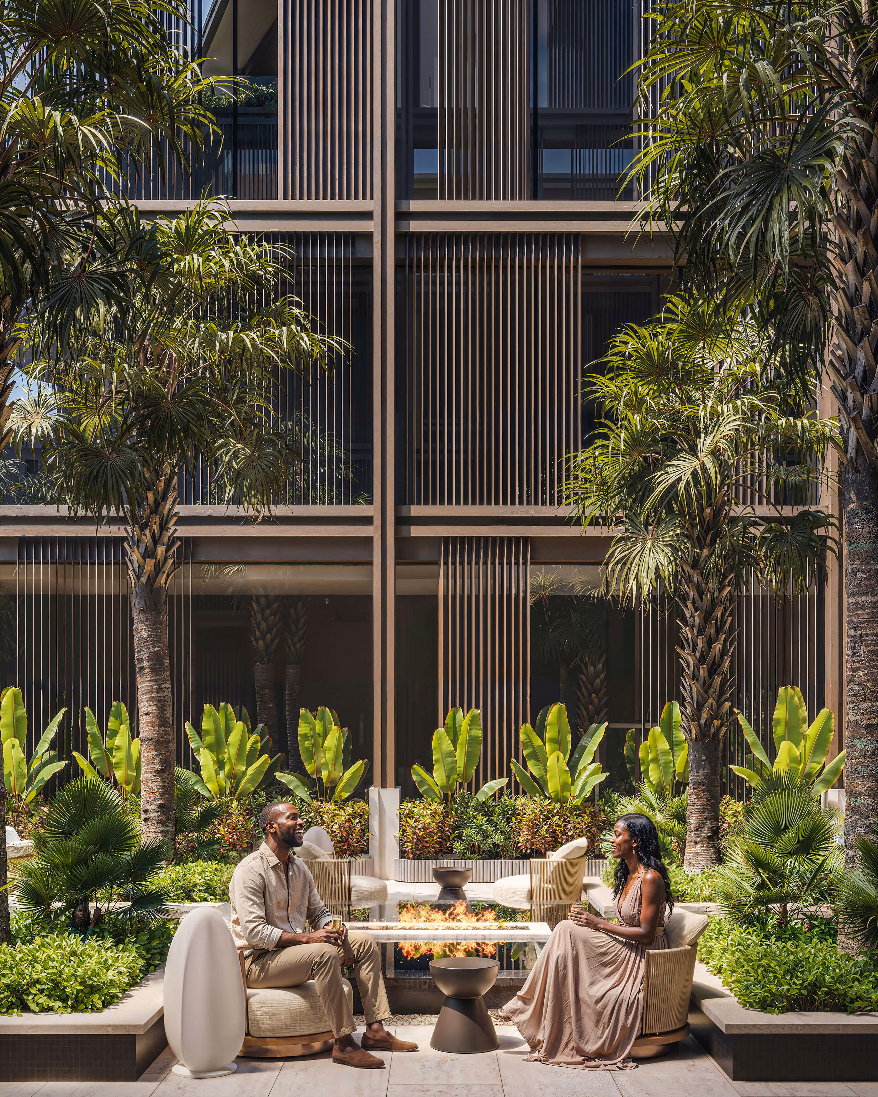 Aqquaaba courtyard lounge facing a facade of vertical slats and palms.