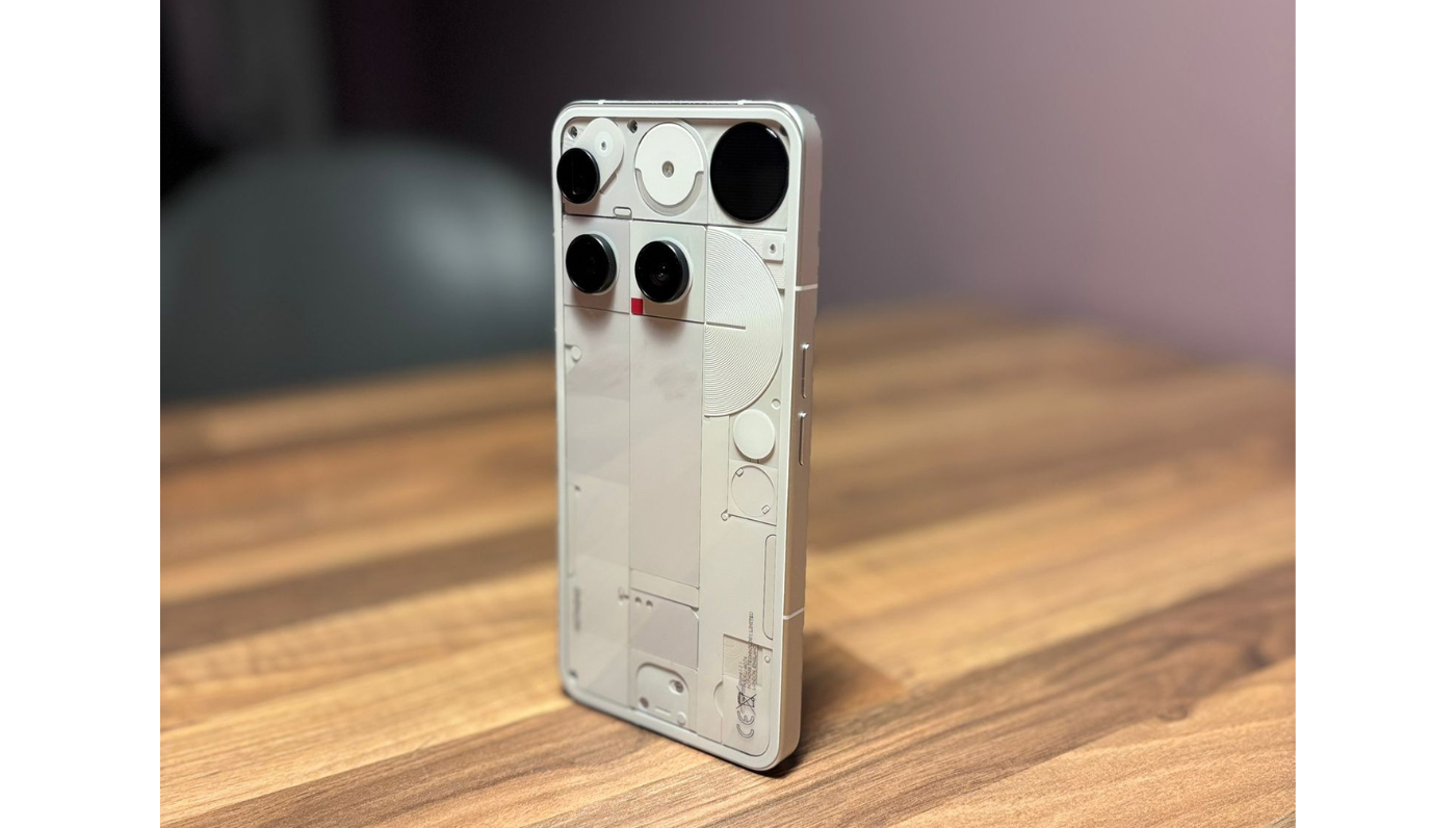 Nothing Phone (3) rear view on wooden desk, showcasing semi-transparent design and dual cameras.