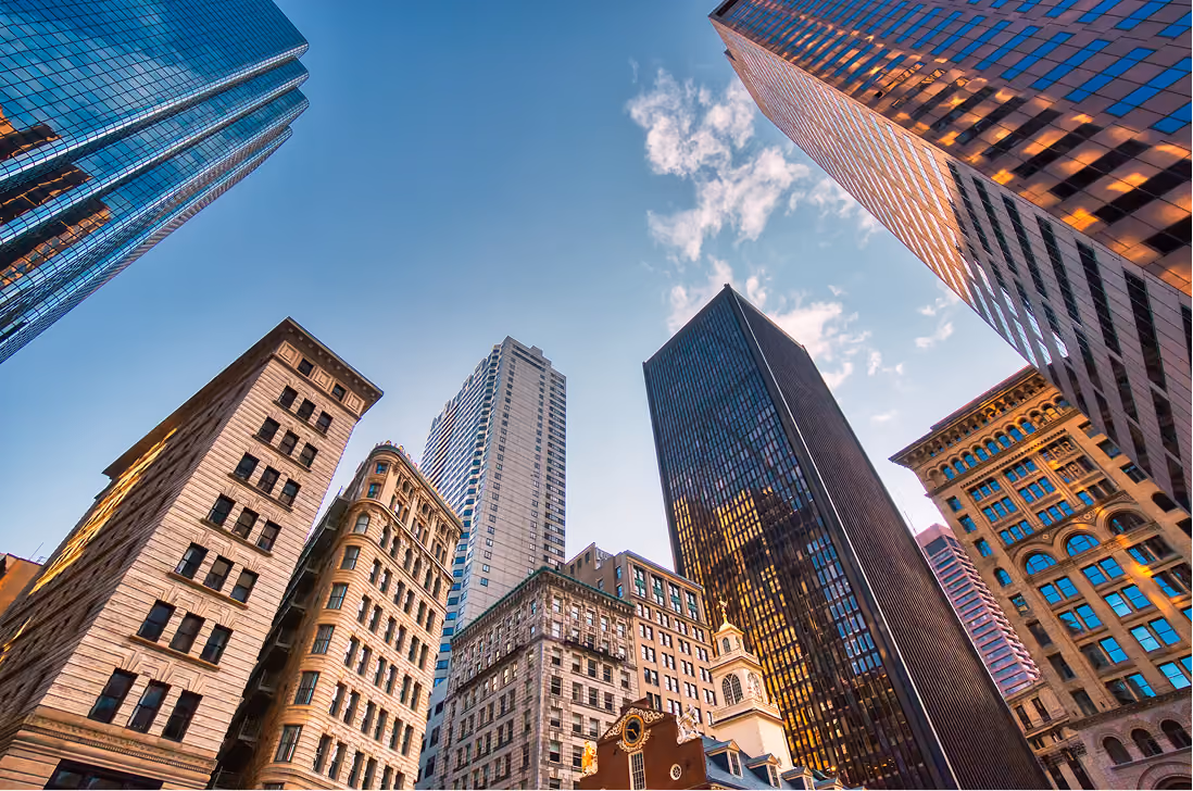 Upward perspective of multiple tall city skyscrapers and historic buildings