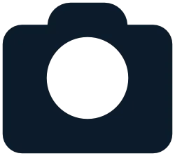 Icon of a camera silhouette with a round lens in the center on a white background.