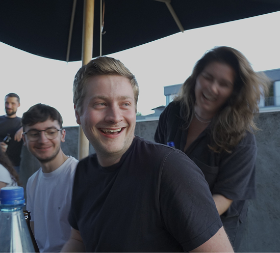 Mitarbeiter lachen gemeinsam auf der Dachterrasse bei einem Agentur-Event.