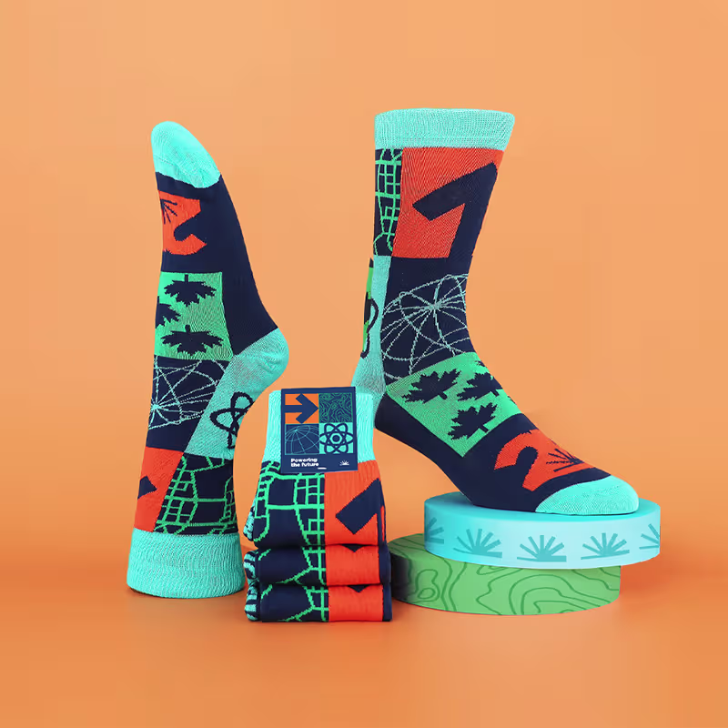 Colorful patterned custom socks with teal toes and cuffs displayed on orange background with stacked platforms.