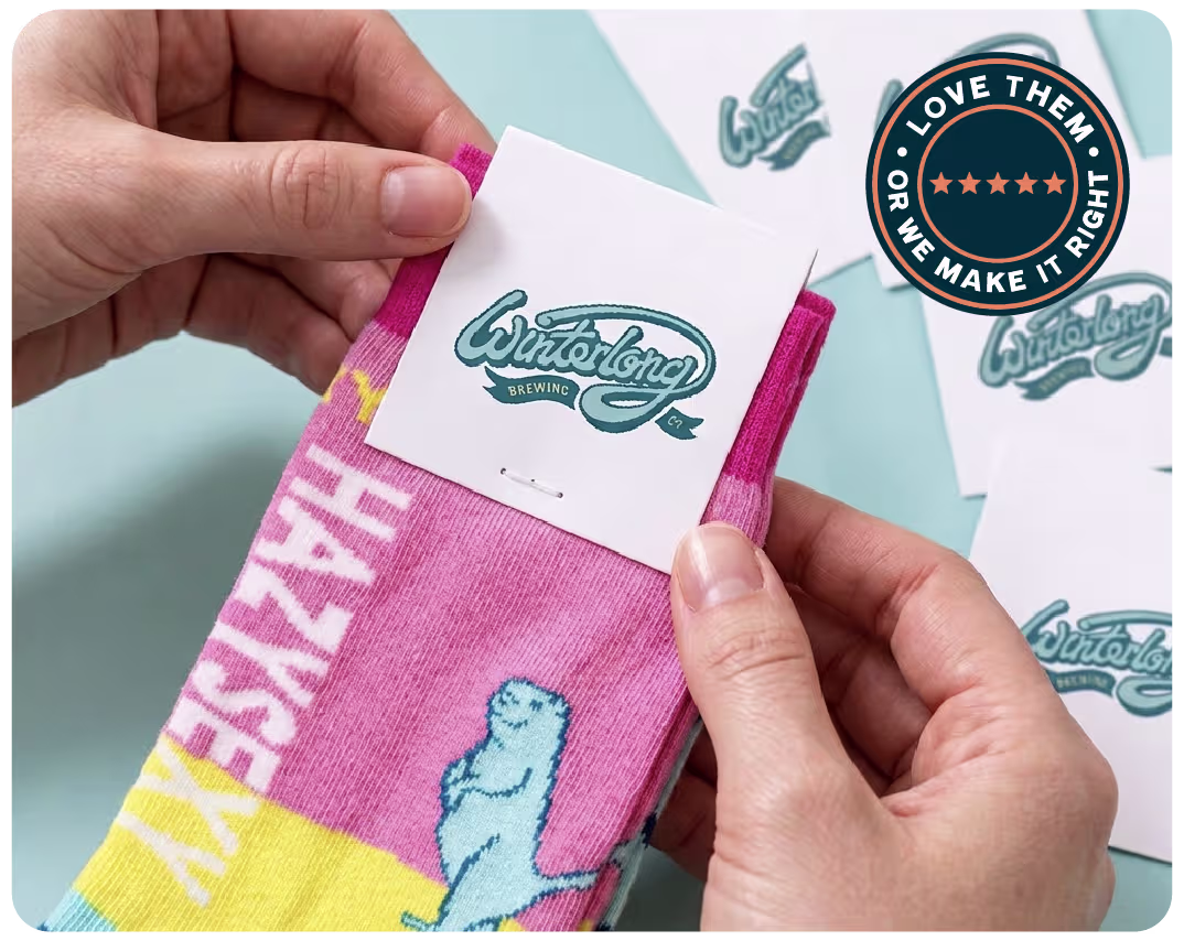 Hands holding a custom sock with a branded header label and a Love Them Or We Make It Right guarantee badge