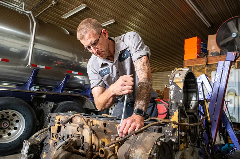 Long Prairie Fleet Maintenance technician Chuck repairs a heavy-duty truck transmission in the shop.
