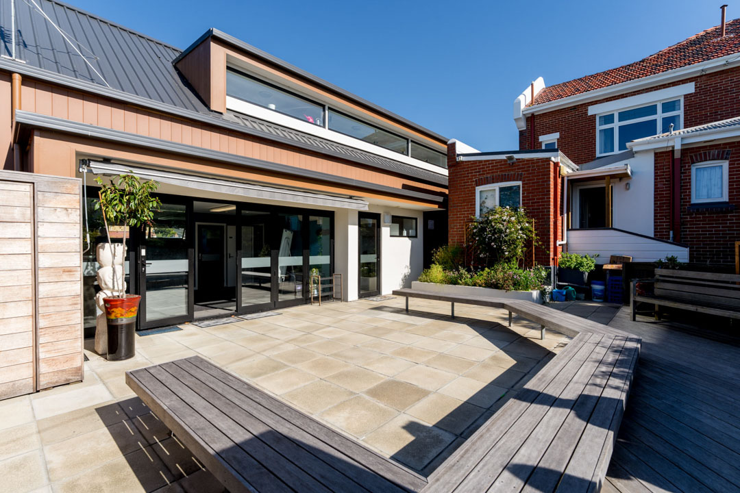 Sunny courtyard outside one of the Residential Programmes' houses, showing a bench seat and plants
