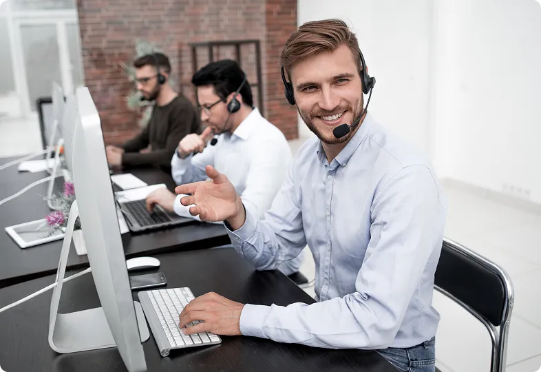 Three men in formal attire standing and discussing something on a laptop.