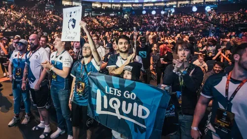 Team Liquid fans cheering at an esports event with a large flag.