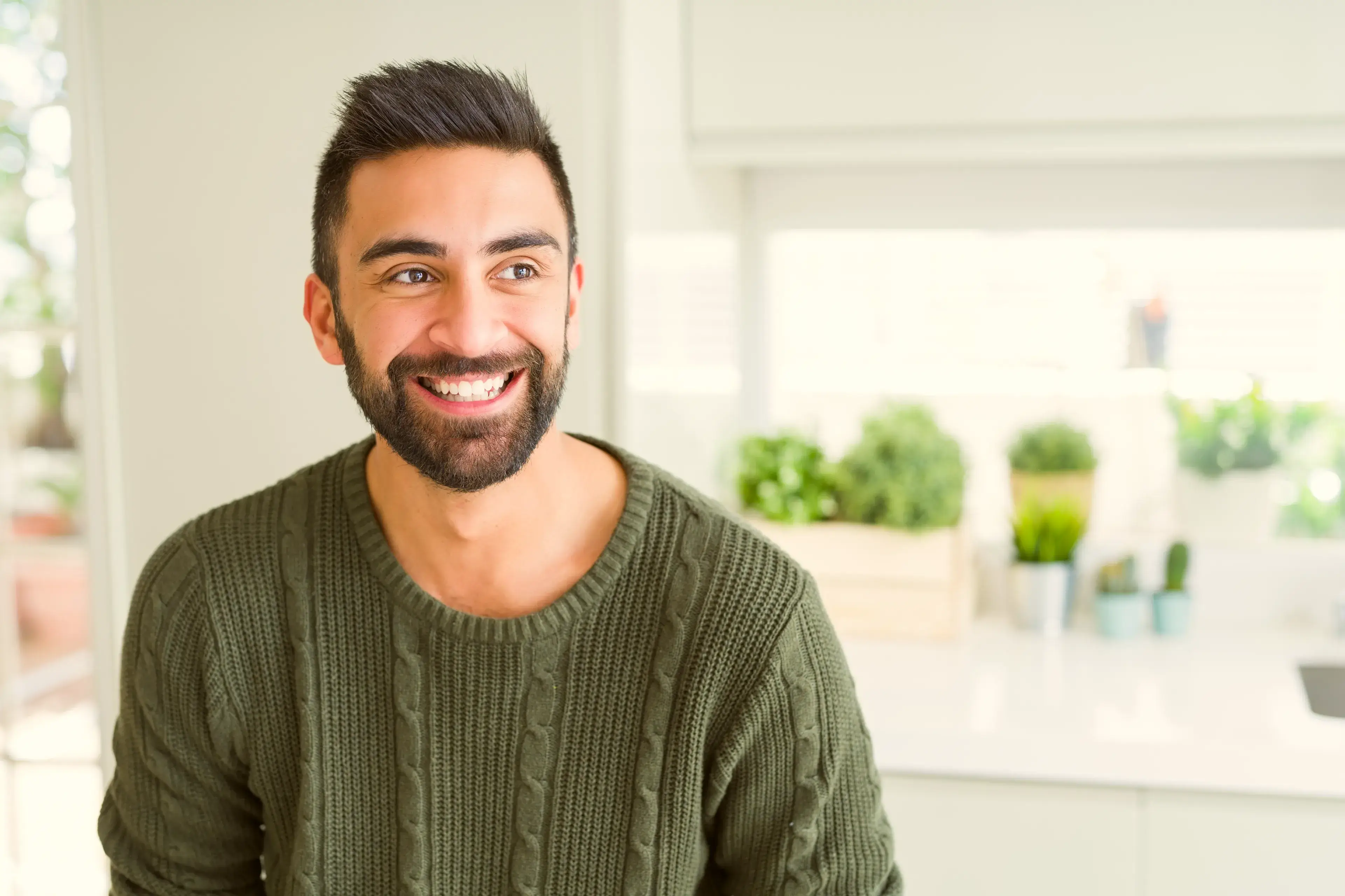 a smiling man in a green sweater in a kitchen