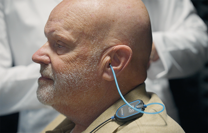Audiologist performing Real-Ear Measurement hearing aid verification with probe tube in patient's ear
