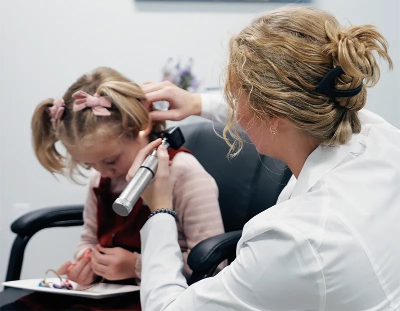 Audiologist examining a pediatric patient with an otoscope