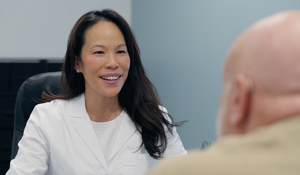 Image of an audiologist sitting with a patient during a hearing aid consultation