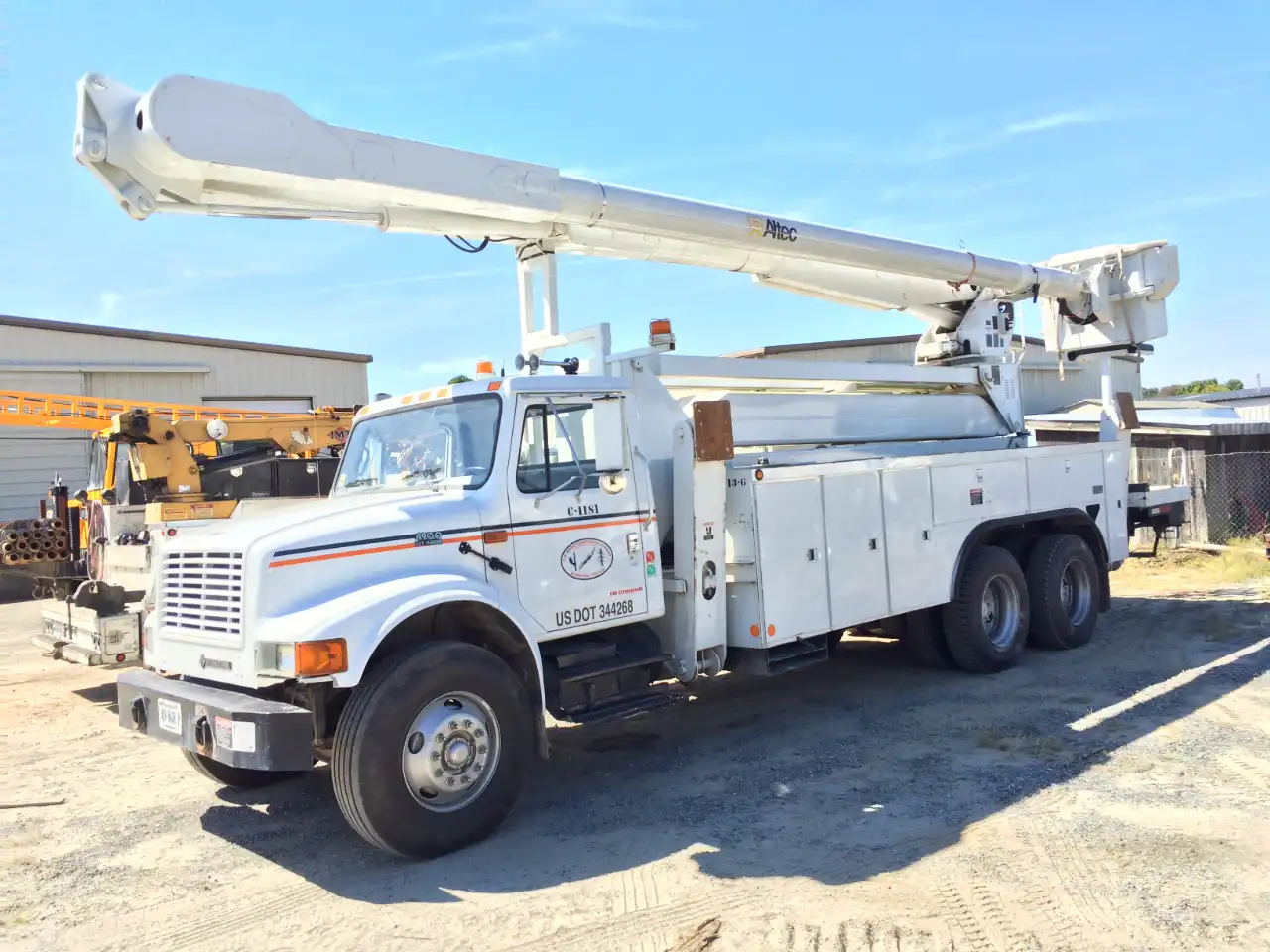 Bucket truck prepped for hydraulic boom service; Altec arm extended on white International, door reads “US DOT 344268.”