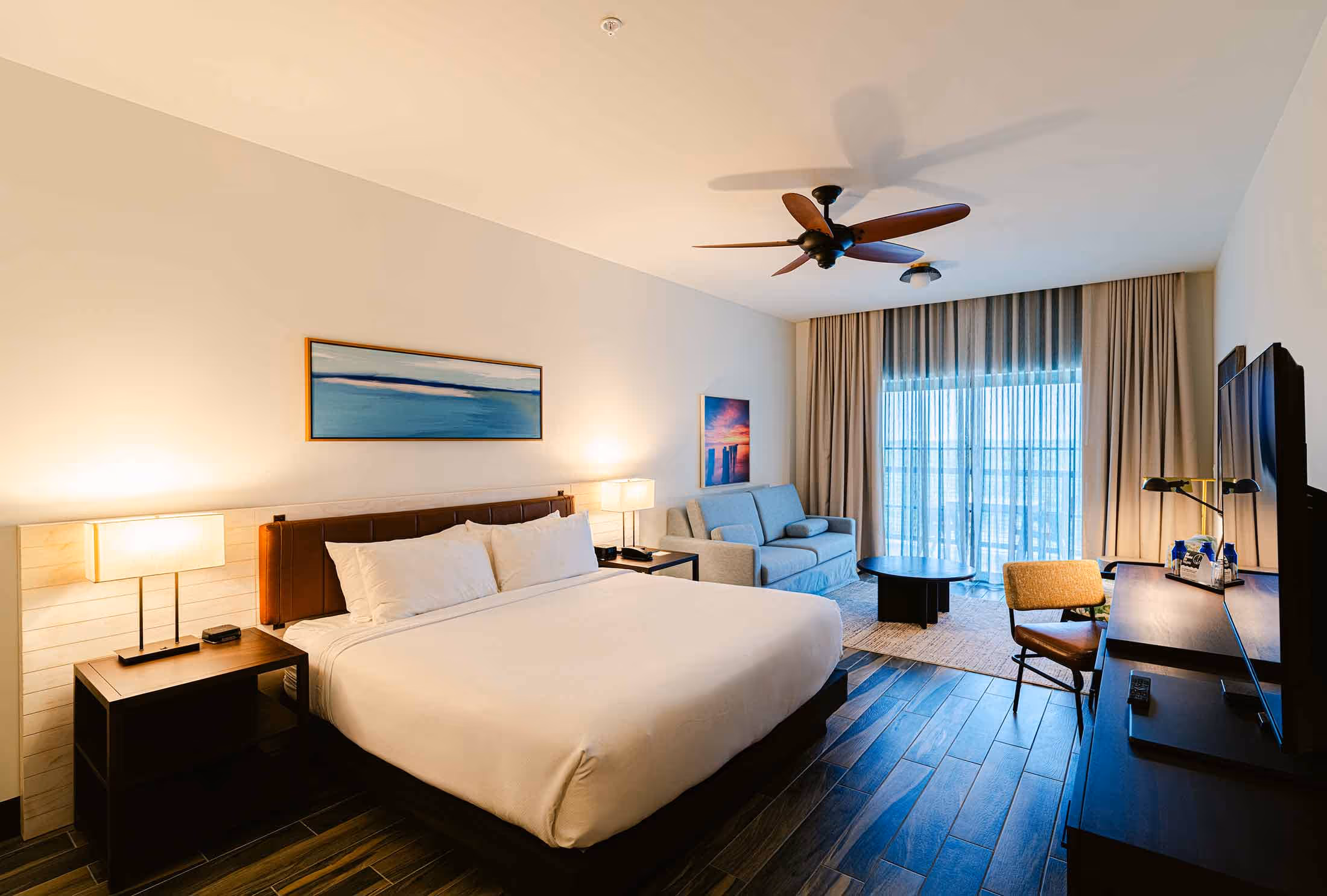 One of the bedrooms at the hotel with a fan, bed, desk, etc.