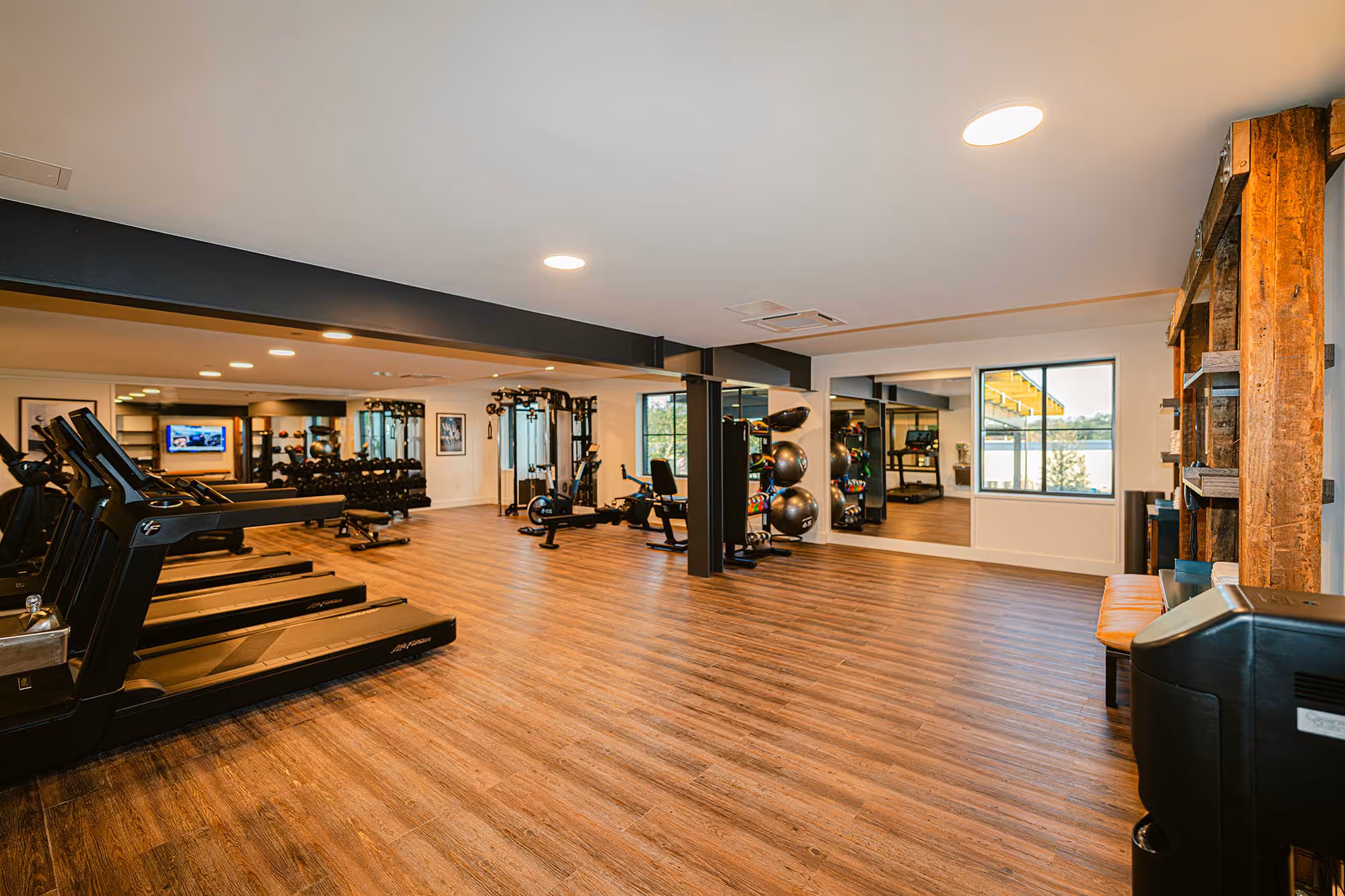 Bright gym with cardio, weights, and mirrors.