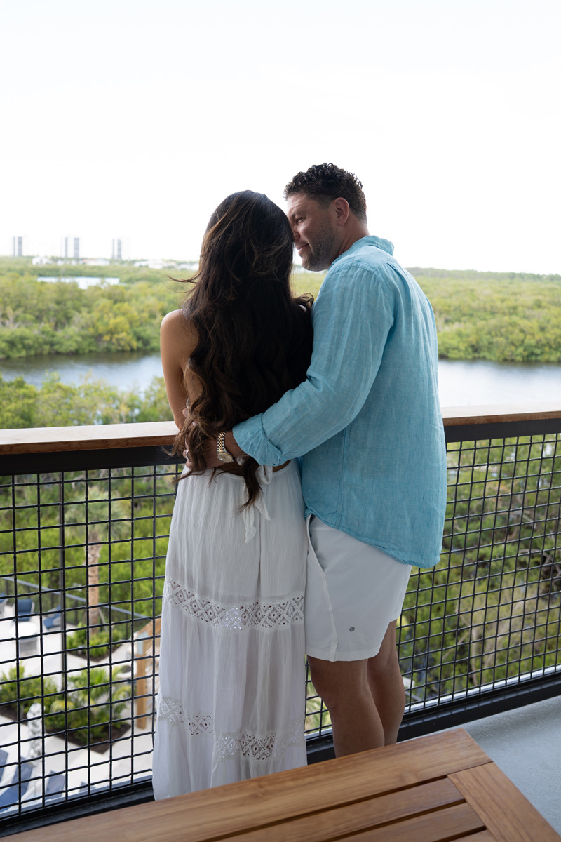 Couple embracing on balcony overlooking lush river landscape
