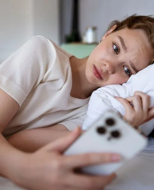 Young person looking at phone while lying down
